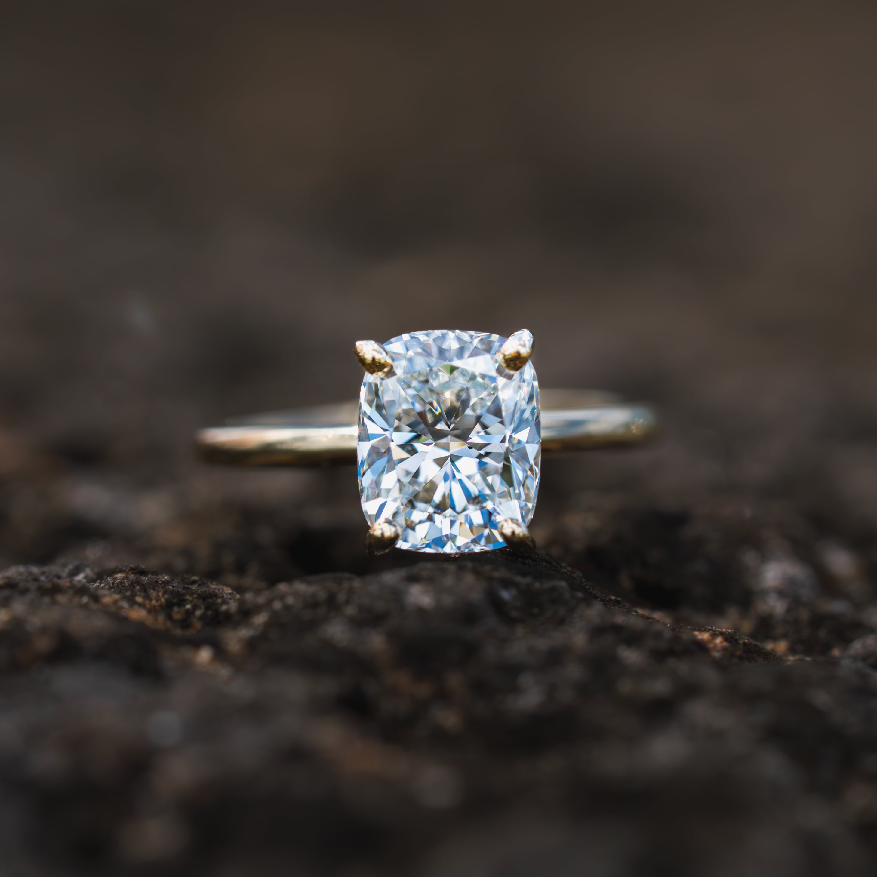 Custom Cushion Cut Diamond ring on a dark, textured surface