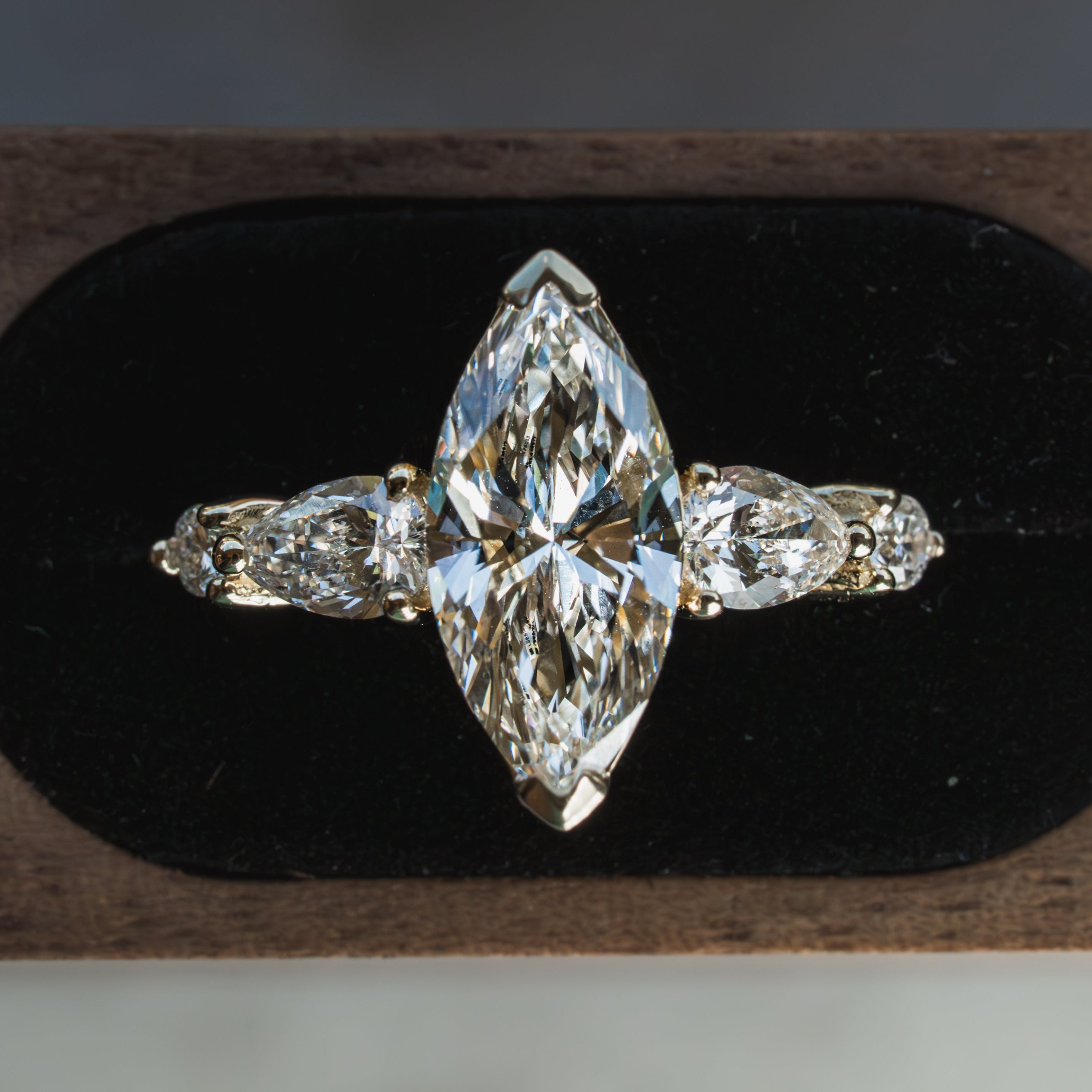 Custom Marquise diamond ring on a black cushion with a wooden base