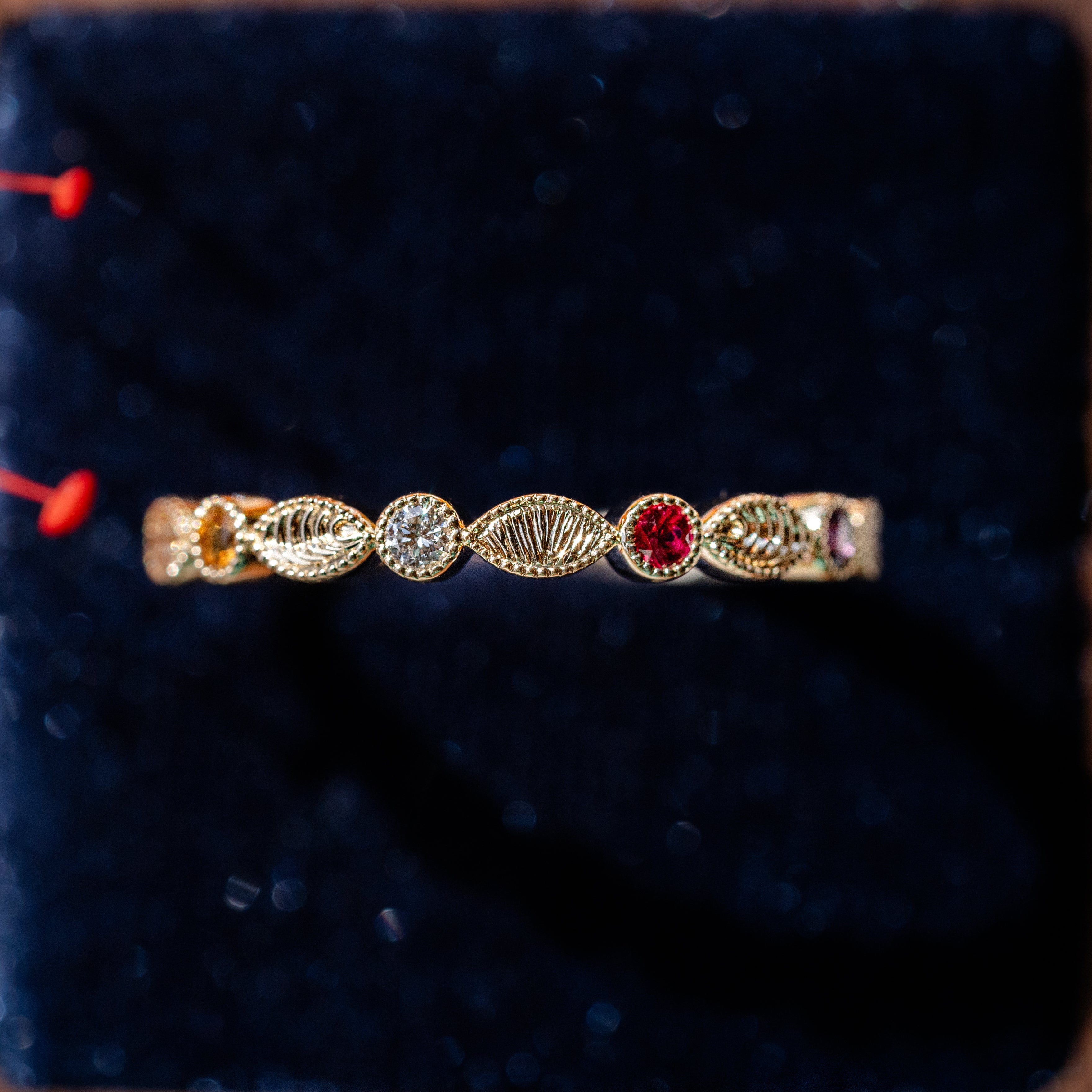Gold ring with gemstones on a dark blue cushion