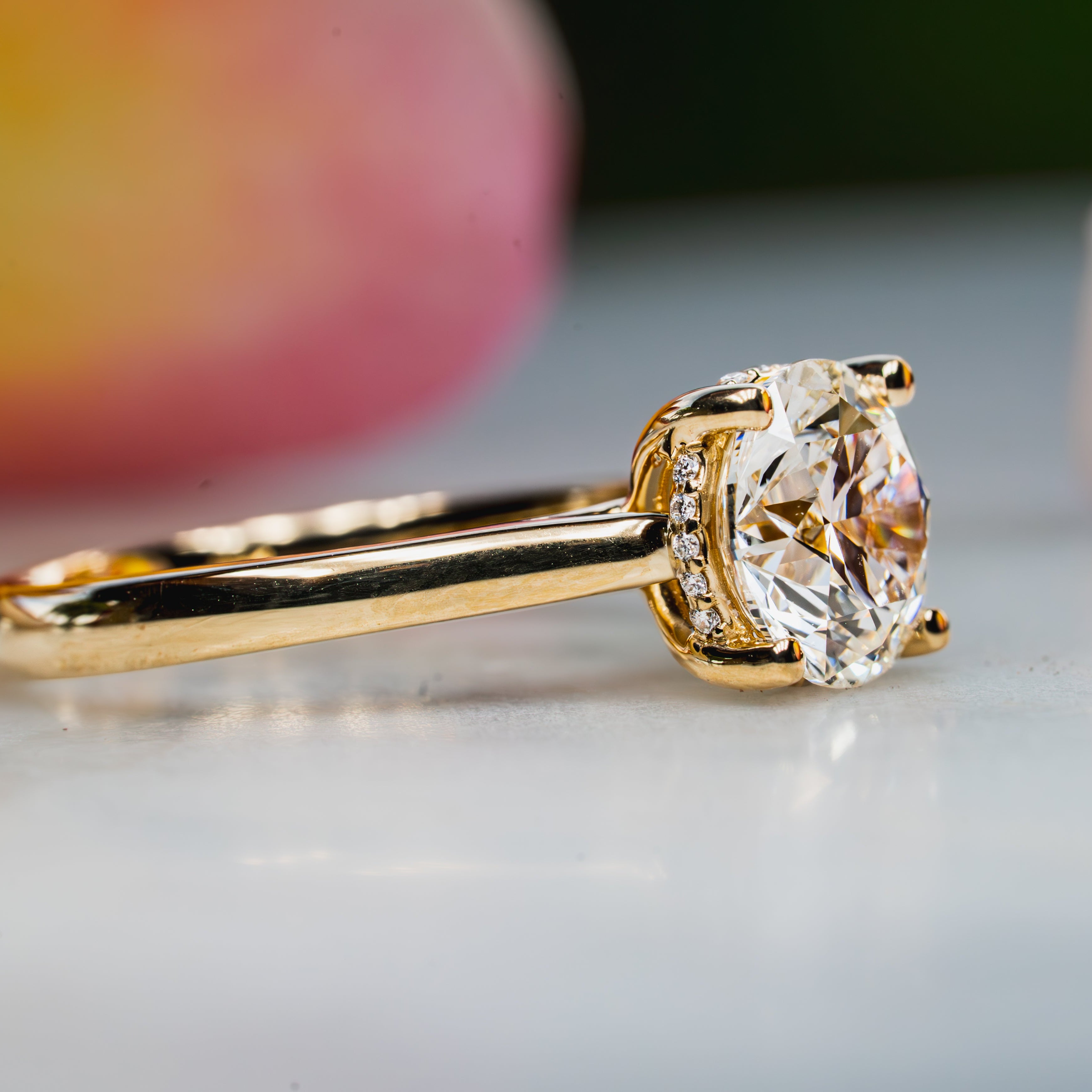 Custom 18ky Gold ring with a round natural diamond on a light surface