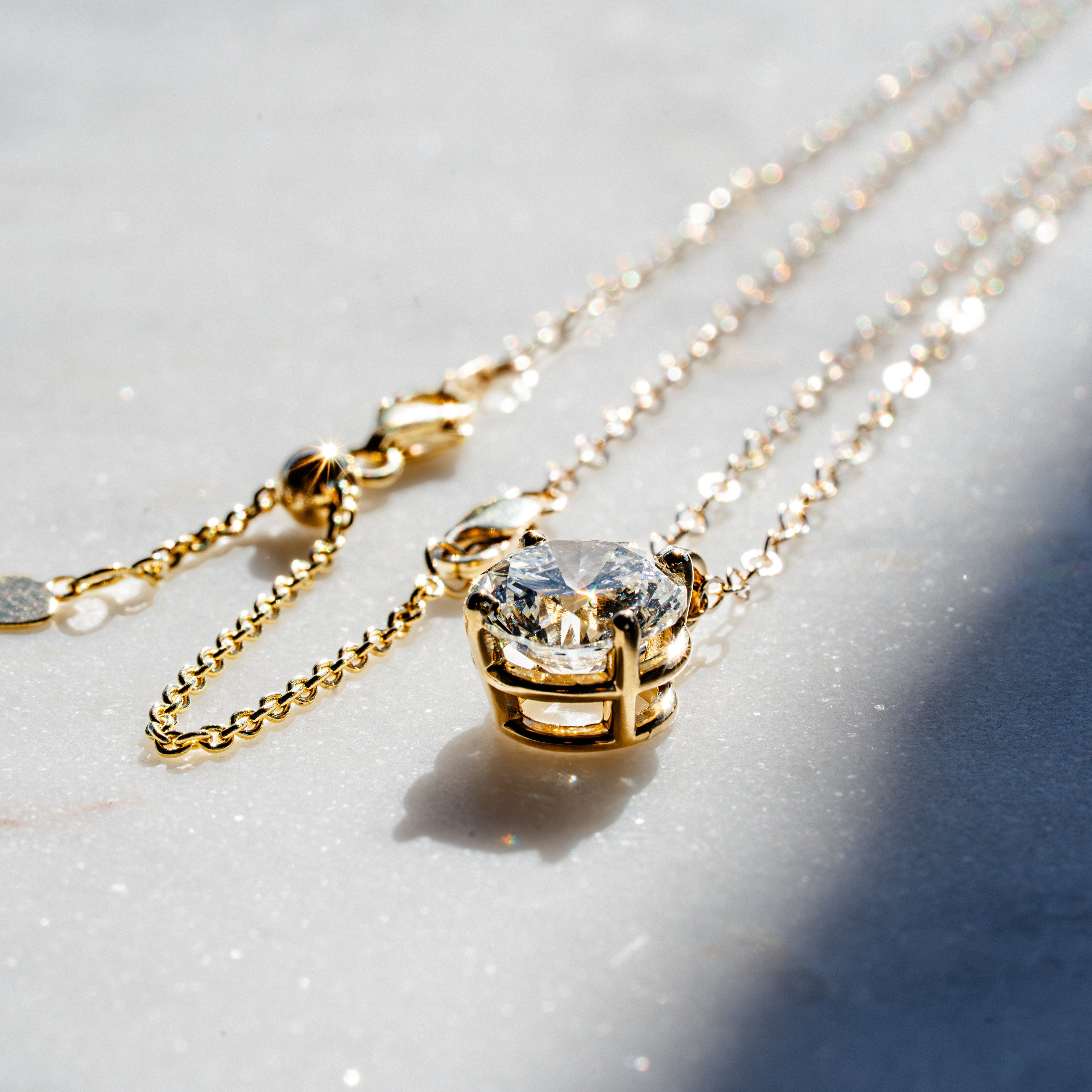 Gold necklaces with diamond pendants on a light background
