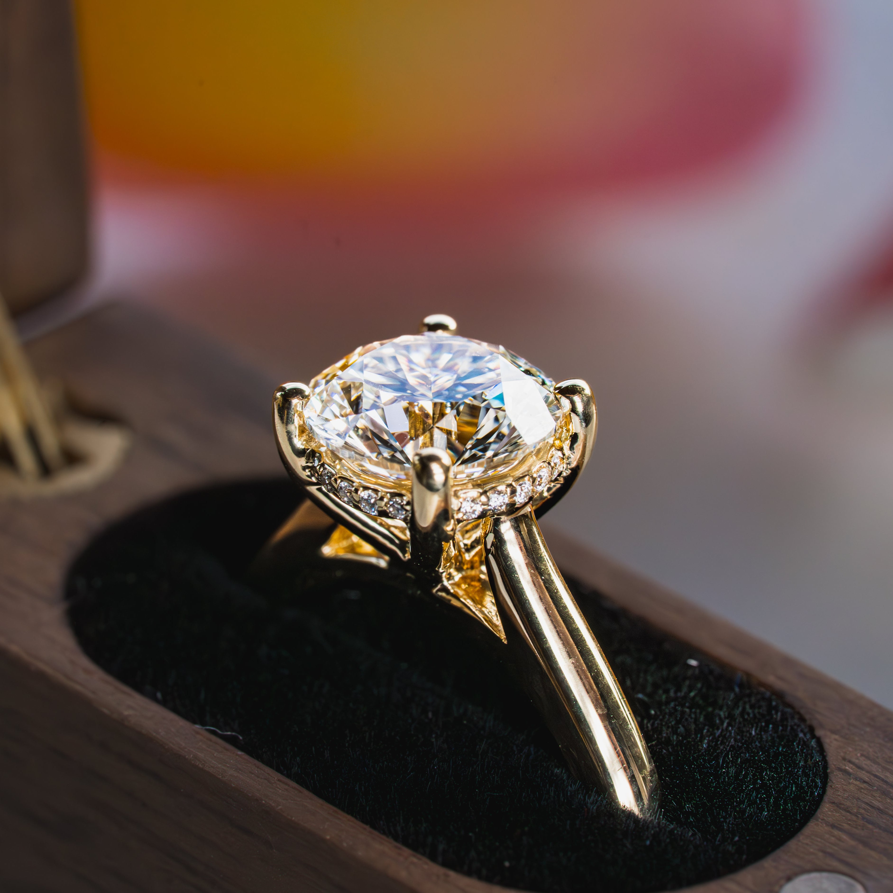 Gold ring with a large diamond on a black stand against a blurred background