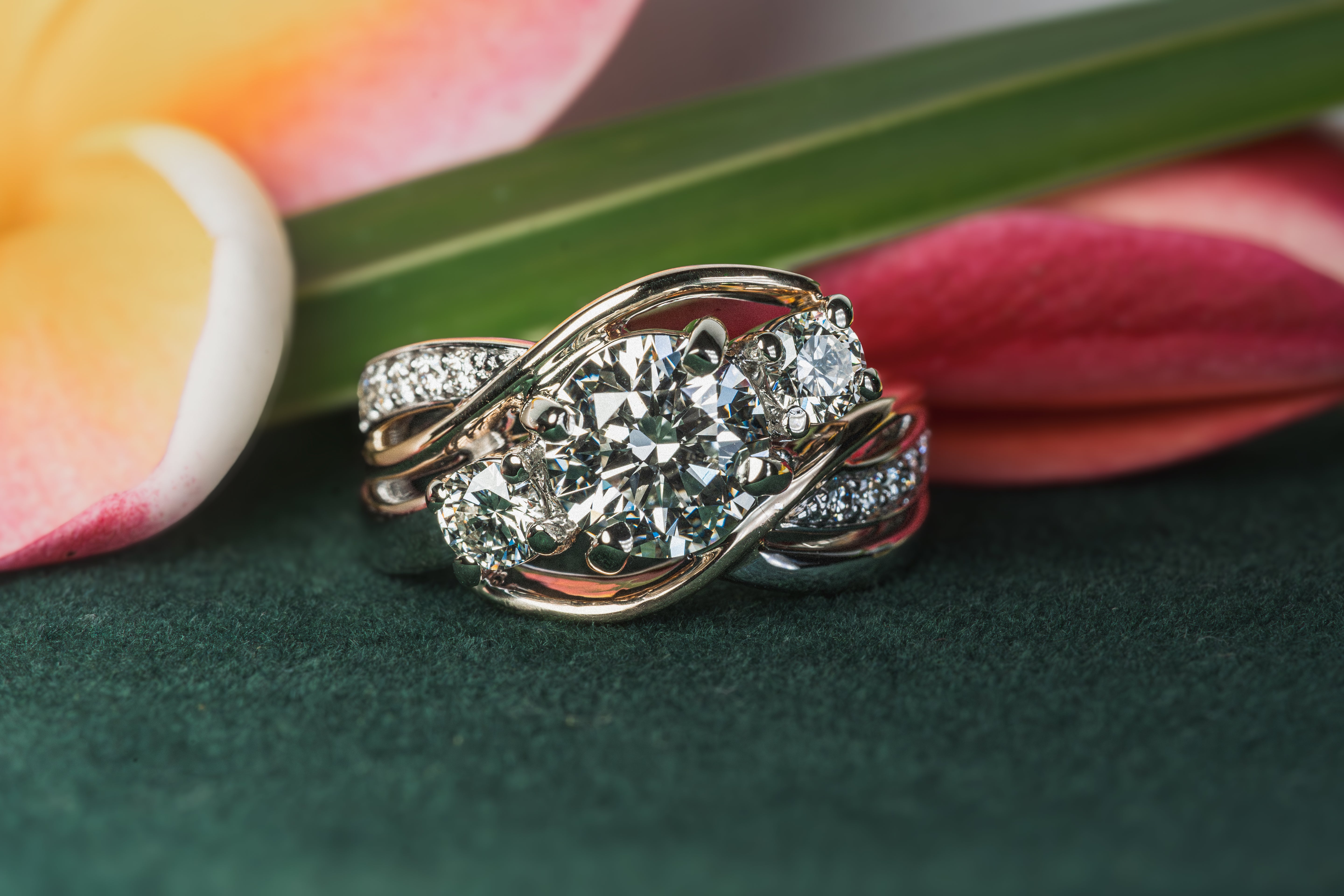 White Gold ring with diamonds on a green surface with flowers in the background
