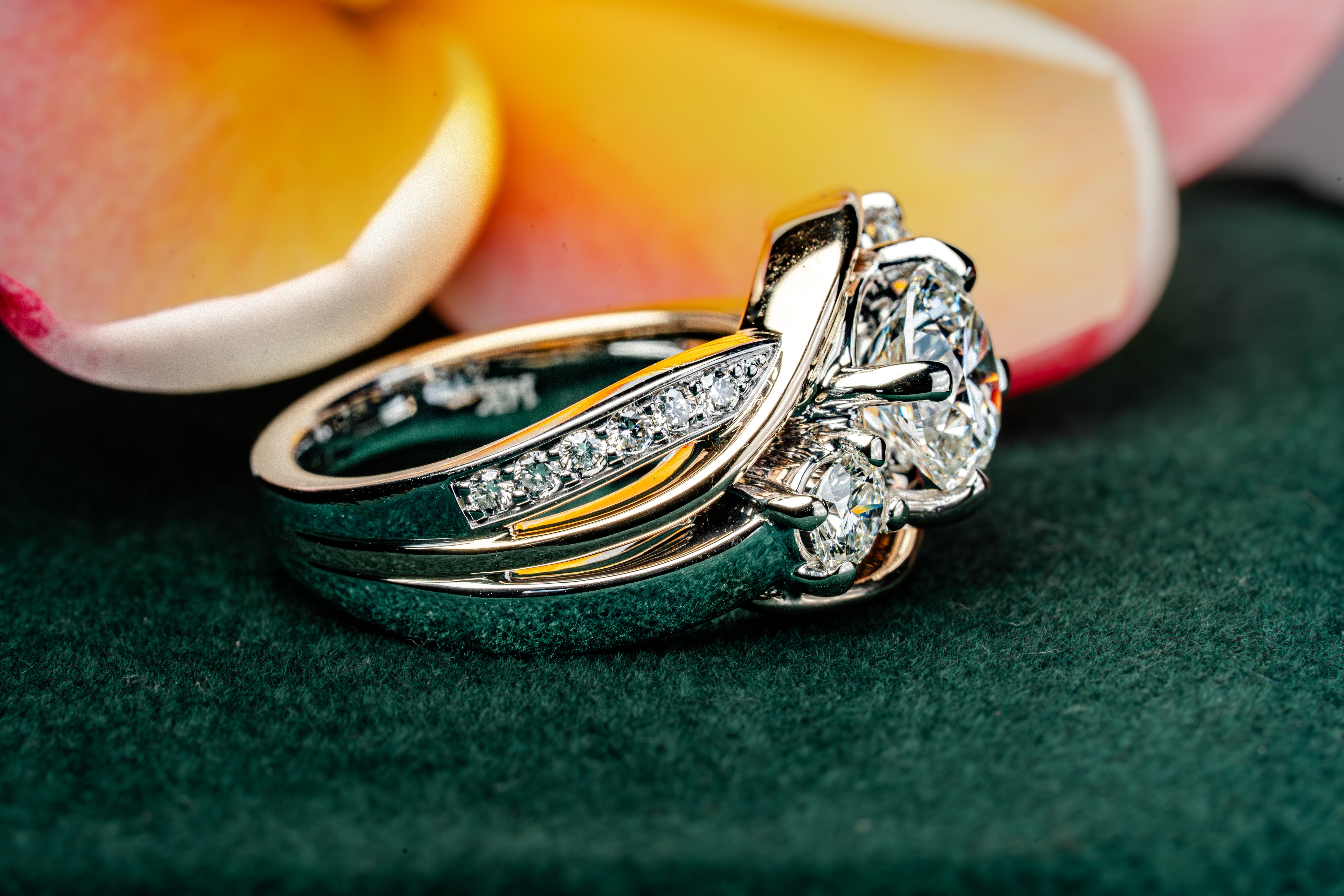 Nalu Ring Kauai Custom Jewelry on a green surface with plumeria background